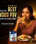 Woman enjoying the BEST VADA PAV at home with tasty chutneys and packaging on the table.