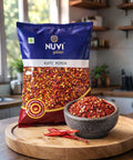 NUVI Kuti Mirch, crushed red chilli in a bowl, package in the background, vibrant spice mix on a wooden table.